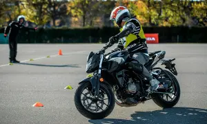Persona con casco y chaleco amarillo practica en moto en circuito con conos. ¡Así me puedo sacar el carnet A directamente!