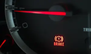 El panel de un coche muestra una luz de advertencia roja con un signo de exclamación dentro de un círculo y la palabra "BRAKE". Esto indica que algo no va bien con el sistema de frenos.