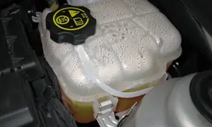 Depósito de expansión con líquido refrigerante y burbujas. Es hora de rellenar líquido refrigerante para mantener el motor fresco.