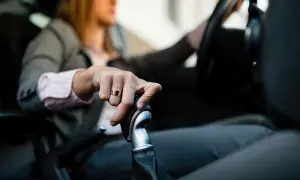 Mano con anillo sobre palanca de cambios, aprendiendo como conducir un coche automático.
