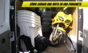 Una moto amarilla lista para transportar en furgoneta, junto a sillas apiladas y mochilas.