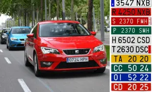 Coches en fila, uno rojo con matrícula H año 0724 HPH, y otros azules y grises. A la derecha, varias matrículas de diferentes colores y formatos.