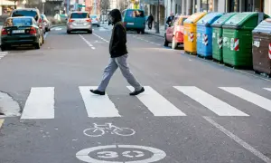 Un hombre cruza la calle por un paso de cebra. Se considera peatón a la persona que camina, y él está haciendo exactamente eso, respetando las normas de tráfico.