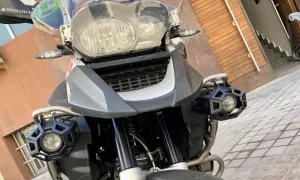 Detalle frontal de una motocicleta con dos luces antiniebla hexagonales negras montadas en los laterales.