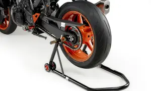 La rueda trasera de una moto deportiva naranja está elevada sobre un caballete basculante negro.