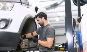 Mecánico revisa el sistema de frenos de un coche, buscando la causa del ruido copelas al girar.