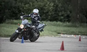 Motociclista en entrenamiento, practicando maniobras para obtener su **permiso a**. Conos marcan el circuito.