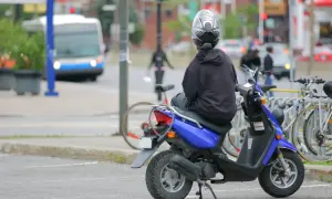 Persona en moto azul, con casco, esperando. ¿Con cuántos años puedes conducir una moto de 49?