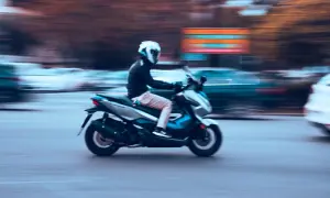 Motorista en moto 125cc, con casco blanco, circulando rápido. La imagen evoca la libertad de movimiento, quizás pensando en la nueva normativa motos 125.