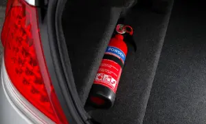 Extintor rojo en el maletero de un coche, listo para emergencias. Es obligatorio llevar extintor en el coche.