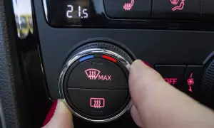 Dedo girando el dial para desempañar cristales coche. Muestra la temperatura 21.5 y el icono de desempañado.