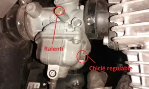 Detalle de carburador de moto, mostrando el tornillo de ralentí y el chiclé regulable.