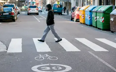 Un hombre cruza la calle por un paso de cebra. Se considera peatón a la persona que camina, y él está haciendo exactamente eso, respetando las normas de tráfico.