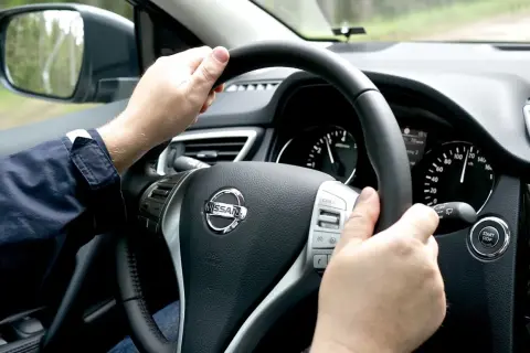 Manos al volante de un Nissan, el velocímetro marca 120 km/h. Se siente una ligera vibración.