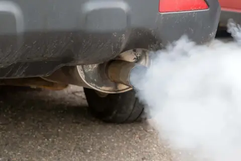 El tubo de escape de un coche emite una densa nube de humo blanco.
