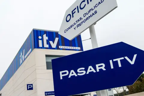 Edificio de ITV con señalización azul que indica "Pasar ITV". Si no pasas la ITV, podrías tener problemas.