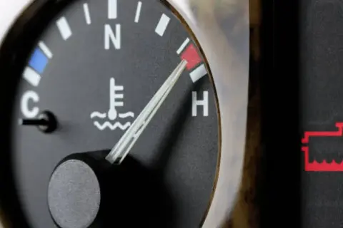 Indicador de temperatura del aceite del coche en rojo, cerca de "H". Alerta de batería encendida.