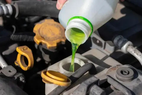 Vertiendo anticongelante verde en el motor. No se recomienda mezclar anticongelante verde y rosa.