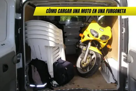 Una moto amarilla lista para transportar en furgoneta, junto a sillas apiladas y mochilas.