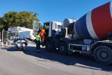 Agente de tráfico supervisa camión hormigonera en una estación de pesaje. La **itv en carretera** es crucial para la seguridad vial.