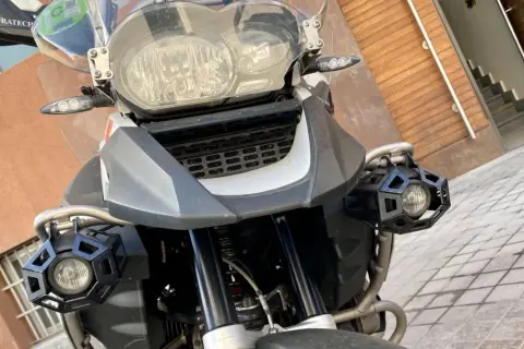 Detalle frontal de una motocicleta con dos luces antiniebla hexagonales negras montadas en los laterales.