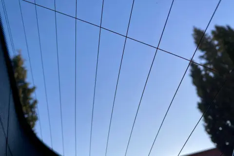 Líneas finas cruzan el cielo azul claro, reflejando la luneta térmica de un coche.