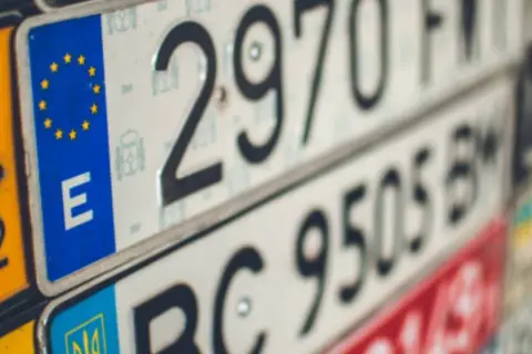 Varias nuevas matrículas de vehículos, algunas con el emblema de la UE y la letra "E", otras con números y letras.