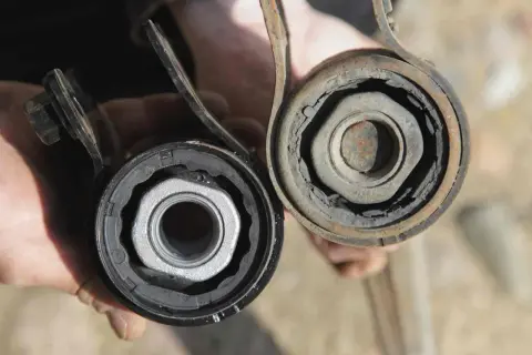 Comparación de un silentblock nuevo y uno desgastado. El nuevo es negro y el viejo está roto y oxidado.