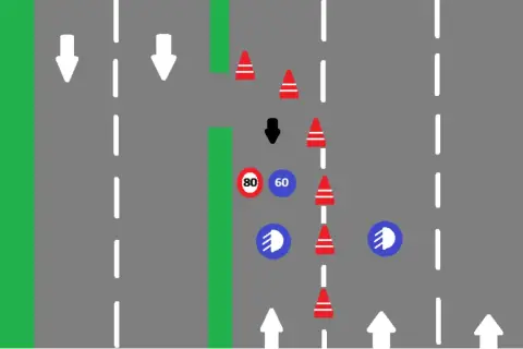 Conos rojos y señales de tráfico indican que es un carril especial. Flechas blancas marcan la dirección.