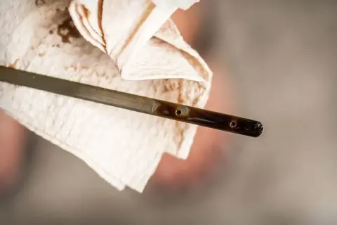 Medidor de aceite de coche con líquido oscuro, mostrando cómo se mira el aceite del coche.