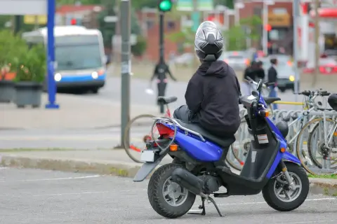 Persona en moto azul, con casco, esperando. ¿Con cuántos años puedes conducir una moto de 49?