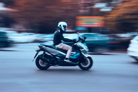 Motorista en moto 125cc, con casco blanco, circulando rápido. La imagen evoca la libertad de movimiento, quizás pensando en la nueva normativa motos 125.