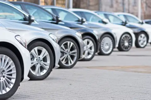Una fila de coches modernos, mostrando diferentes tipos de aparcamiento y diseños de llantas.
