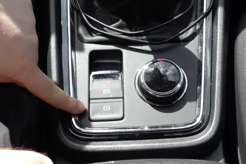 Dedo presionando el botón de freno de mano electrónico, que es parte del sistema auto hold.