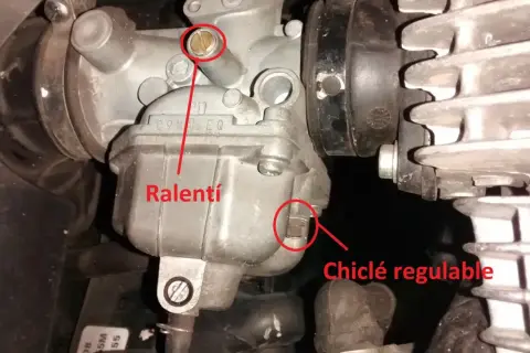 Detalle de carburador de moto, mostrando el tornillo de ralentí y el chiclé regulable.