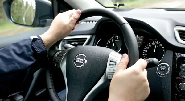 Manos al volante de un Nissan, el velocímetro marca 120 km/h. Se siente una ligera vibración.