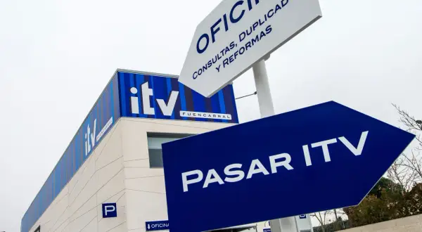 Edificio de ITV con señalización azul que indica "Pasar ITV". Si no pasas la ITV, podrías tener problemas.