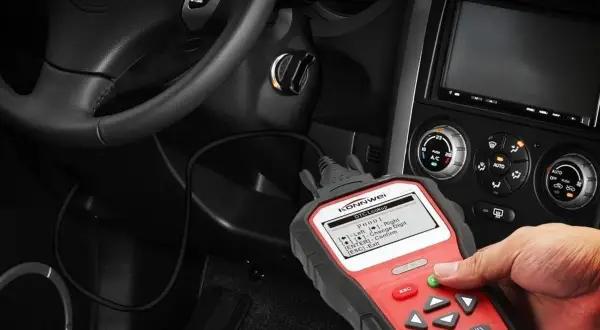 Mano usando un escáner obd coche para diagnosticar un problema. El dispositivo muestra códigos de error.
