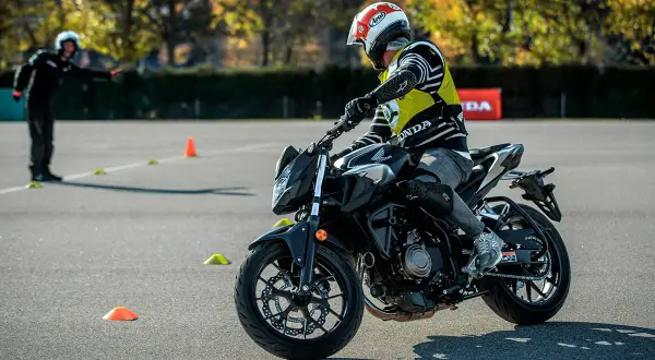 Persona con casco y chaleco amarillo practica en moto en circuito con conos. ¡Así me puedo sacar el carnet A directamente!