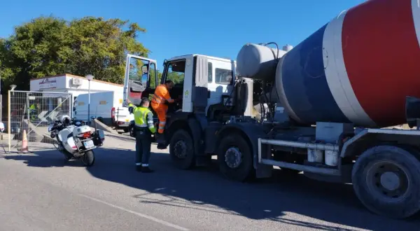 Agente de tráfico supervisa camión hormigonera en una estación de pesaje. La **itv en carretera** es crucial para la seguridad vial.