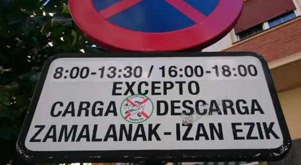 Señal de prohibido estacionar, excepto zona de carga y descarga en horarios específicos.