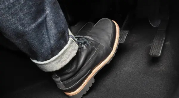 Pie con bota negra pisando el pedal del embrague. Para frenar hay que pisar el embrague y luego el freno.