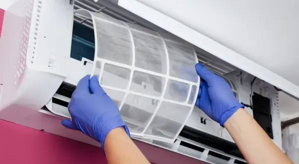 Manos con guantes azules sacan un filtro de aire de un aire acondicionado. Es hora de cambiar filtro aire acondicionado coche para un aire más puro.