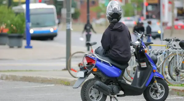 Persona en moto azul, con casco, esperando. ¿Con cuántos años puedes conducir una moto de 49?