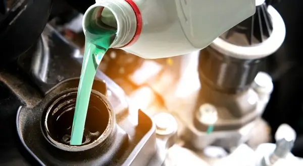 Vertiendo aceite 2T verde brillante en el motor de una motocicleta. El correcto porcentaje aceite 2t es crucial para el rendimiento.