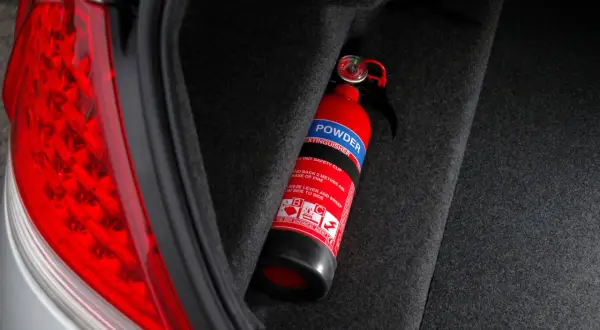 Extintor rojo en el maletero de un coche, listo para emergencias. Es obligatorio llevar extintor en el coche.