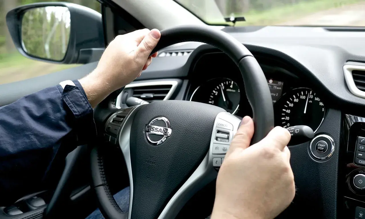 Manos al volante de un Nissan, el velocímetro marca 120 km/h. Se siente una ligera vibración.
