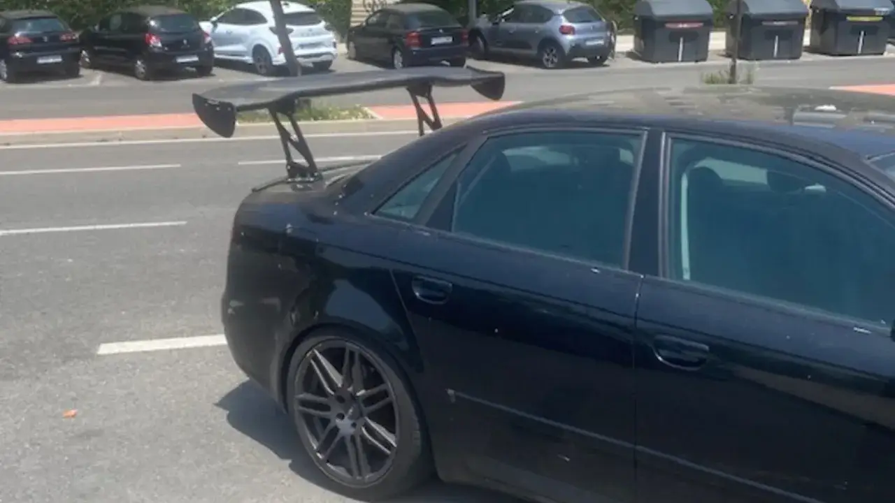 Coche negro con un gran spoiler trasero, listo para la pista.