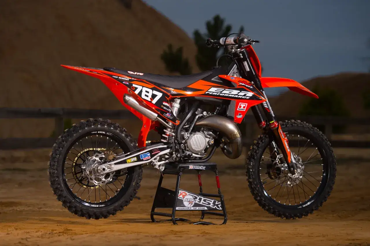 Moto de cross naranja y negra, n&uacute;mero 787, lista para la acci&oacute;n. &iquest;Cu&aacute;ntos caballos tiene una moto de 125cc? &iexcl;Esta tiene potencia!