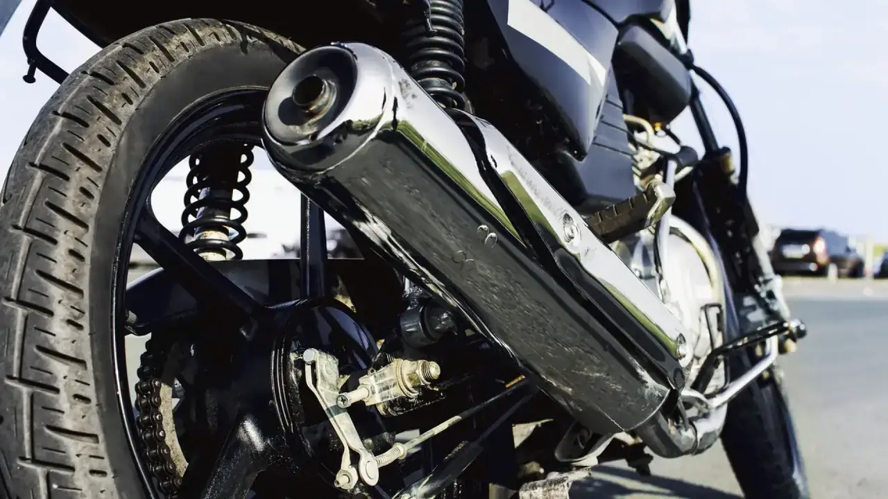 Detalle de la rueda trasera y el escape cromado de una motocicleta. Aunque parezca imposible, una motocicleta puede circular sin tubo de escape.